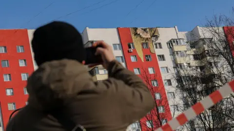 EPA A man takes a photo of a building in Moscow which was hit by a drone attack in March 2025. 